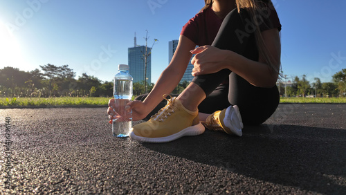 Obraz na płótnie Young attractive sporty woman making pause for drinking water during exercising in the park. w salonie
