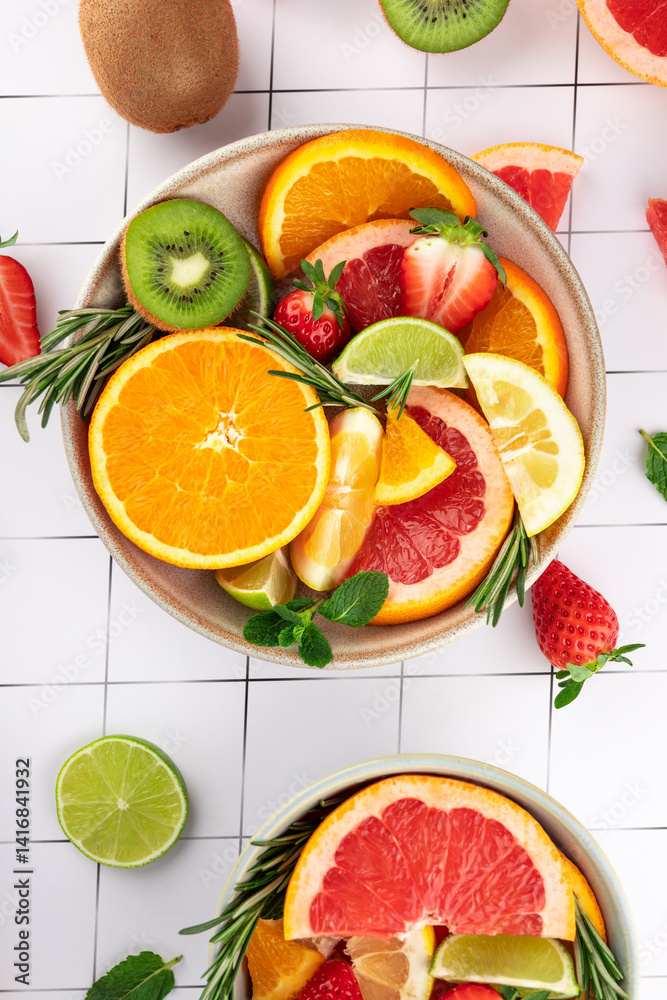 Bright composition of fresh fruits: citrus, kiwi, and strawberries in a bowl on a minimalist background. Healthy and fresh style. Concept of natural food and vitality Bright composition of fresh fruits: citrus, kiwi, and strawberries in a bowl on a minimalist background. Healthy and fresh style. Concept of natural food and vitality