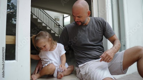 Father with his child daughter sit together hugging at terrace of their house. Dad and kid together at home