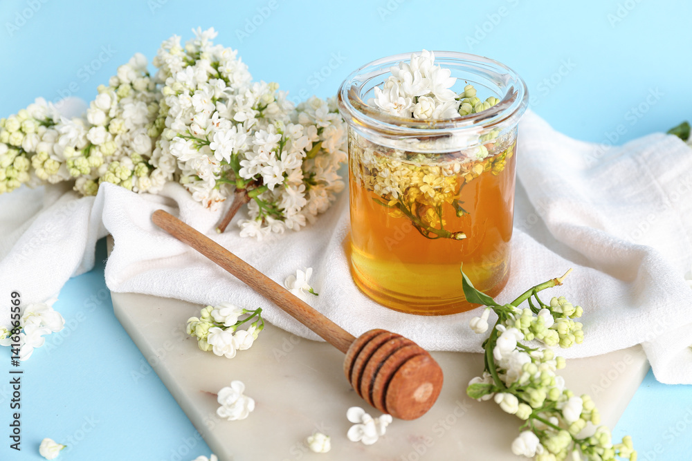 Jar of honey with dipper and white lilac twigs on blue background Jar of honey with dipper and white lilac twigs on blue background