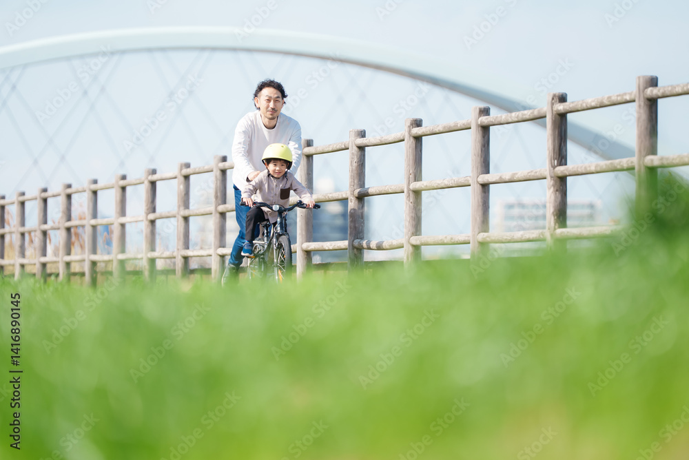 自転車の練習をする5歳の男の子とサポートする父親 自転車の練習をする5歳の男の子とサポートする父親