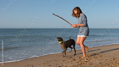 Photos Woman playing fetch with her dog on the beach, having fun