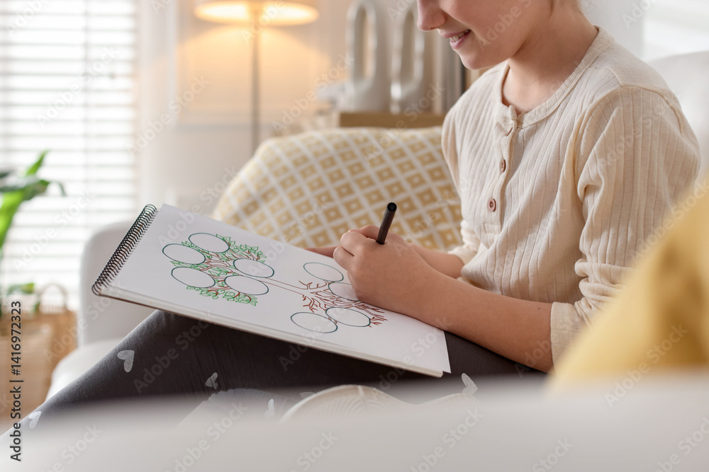 Girl drawing her family tree on sofa indoors, closeup