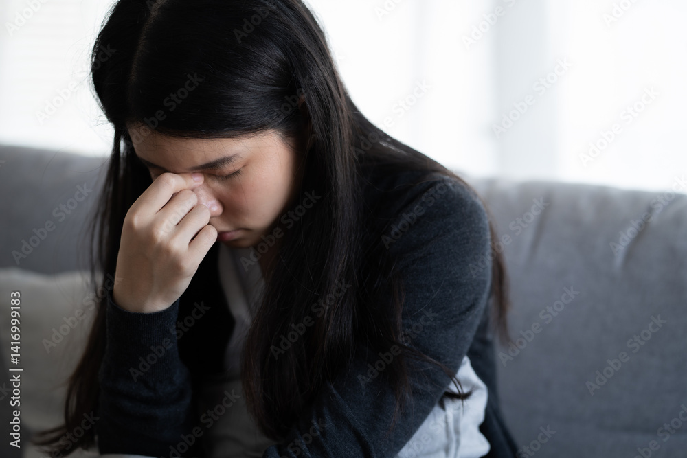 Depressed woman sitting alone on the sofa with hands on head feel stress, sad and worried in the low light environment house Depressed woman sitting alone on the sofa with hands on head feel stress, sad and worried in the low light environment house