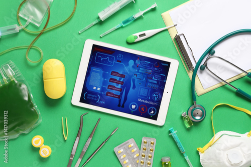 Tablet computer and medical supplies on green background. Telemedicine concept