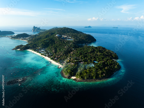 Aerial view of Phi Phi Don island in Thailand with lush green hills, turquoise bays, white sand beaches, and boats along the coastline under a clear blue sky.