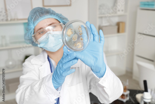 Female scientist with Petri dish in laboratory, closeup