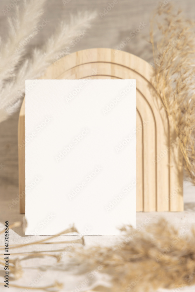 Blank card near dry pampas grass and beige wooden decor on linen closeup, minimal mockup