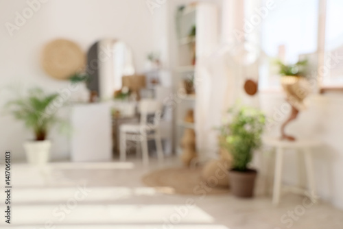 Blurred view of light makeup room with table, clothes rack and plants