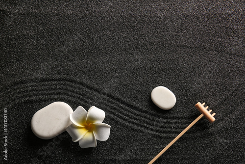 Canvas Print Stones, tropical flower and small rake on black sand with lines