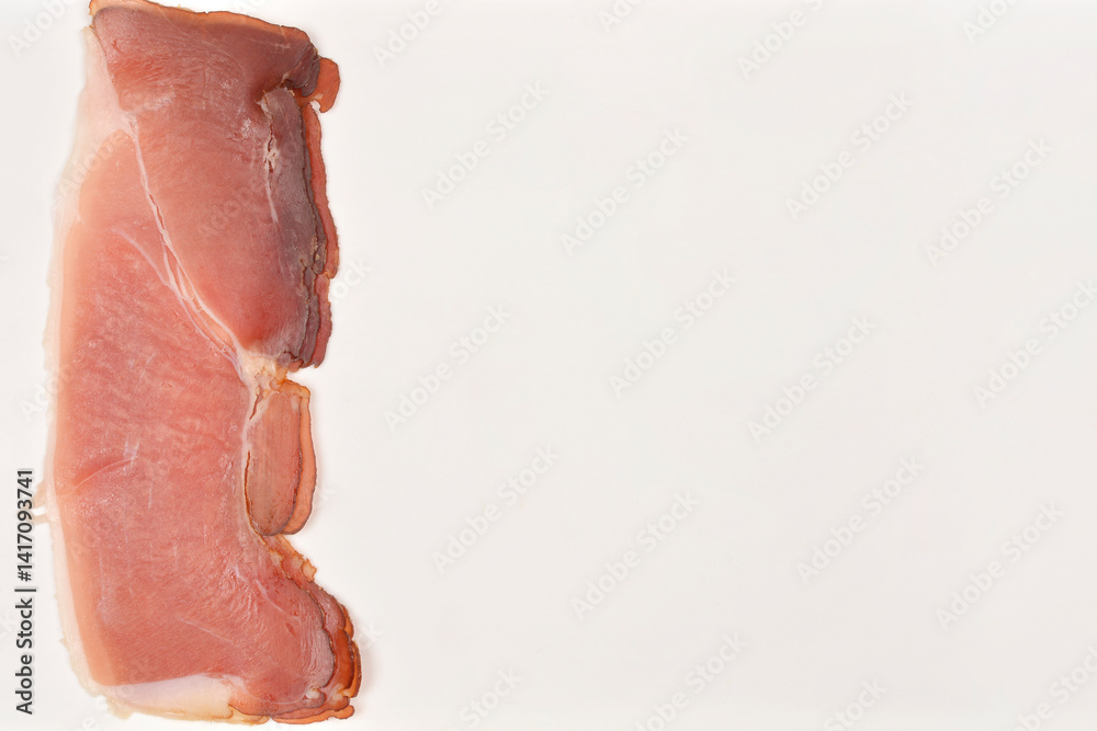 Irregularly shaped slices of thinly dry-cured ham is presented on a plain white background