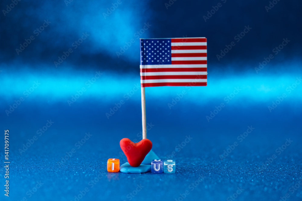 Decorative display of a small American flag with toy letters and a red heart on a blue background