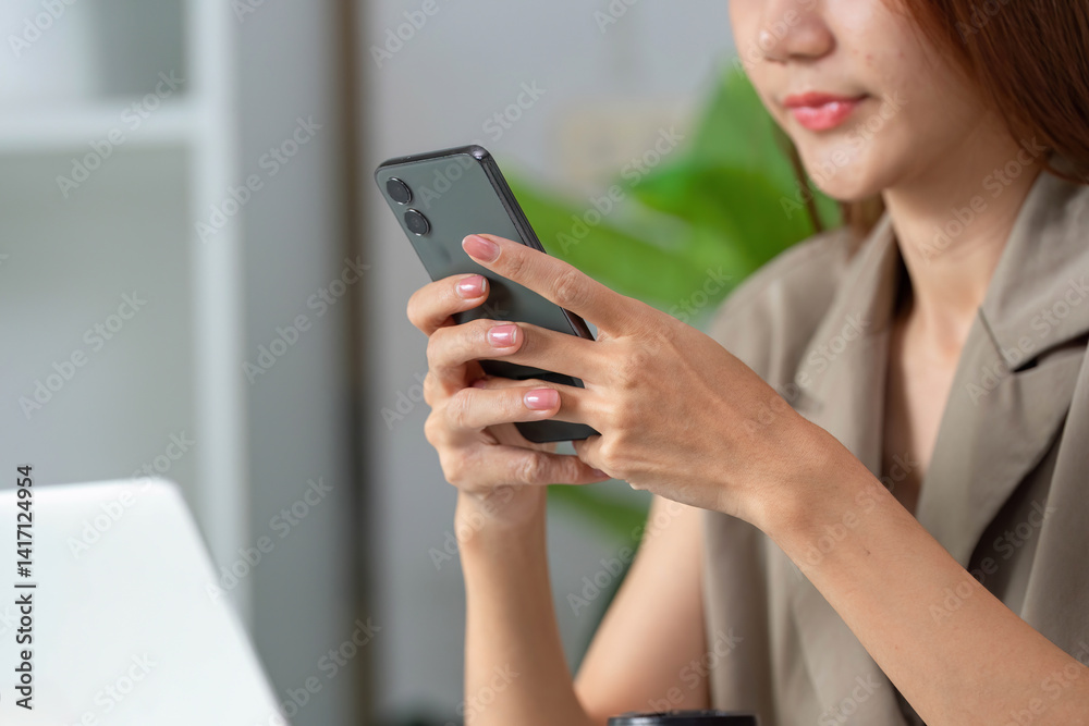 Mobile Technology and Communication. A woman engaging with her smartphone while seated at her desk. Mobile Technology and Communication. A woman engaging with her smartphone while seated at her desk.