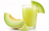 Refreshing light green honeydew melon juice in a glass with fresh melon slices. Sweet and hydrating.