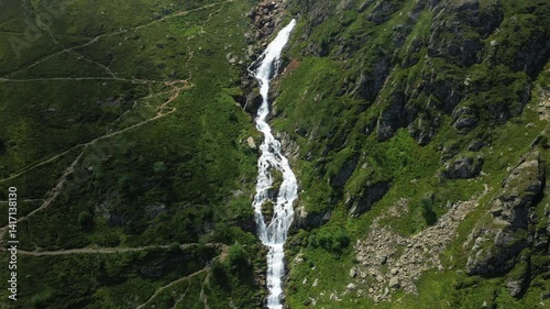 The Lhecou waterfall cascading down the green rocks, in Europe, in France, Occitanie, in the Hautes-Pyrenees, in summer, on a sunny day. 