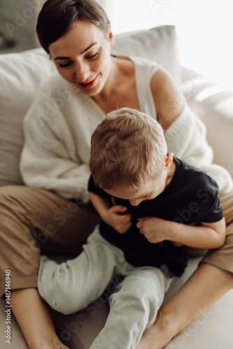 Mother embracing her son while sitting on a sofa: authentic family moments