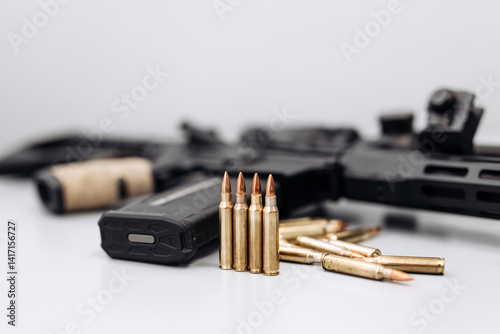 Close-up of firearm with bullets on light background.