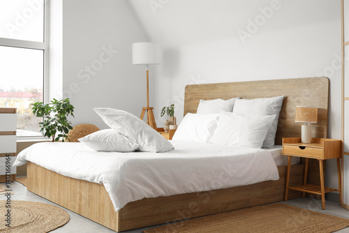 Cozy bed with white blanket and soft pillows in stylish bedroom