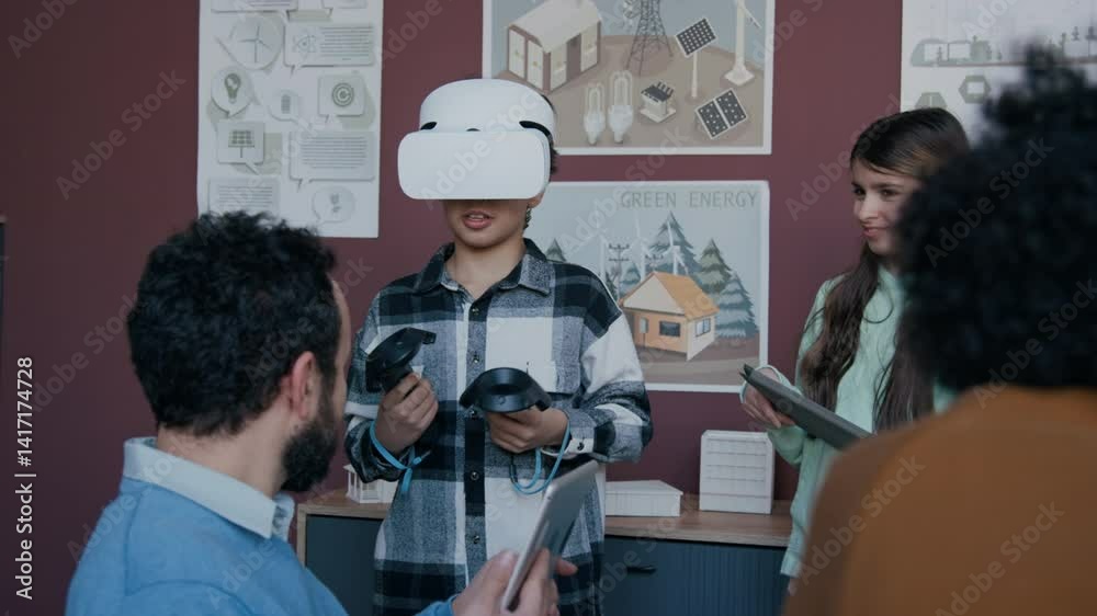 Medium shot of young schoolboy in virtual reality headset and cheerful girl with tablet computer talking to male science teacher, while discussing environmental issues during ecology lesson