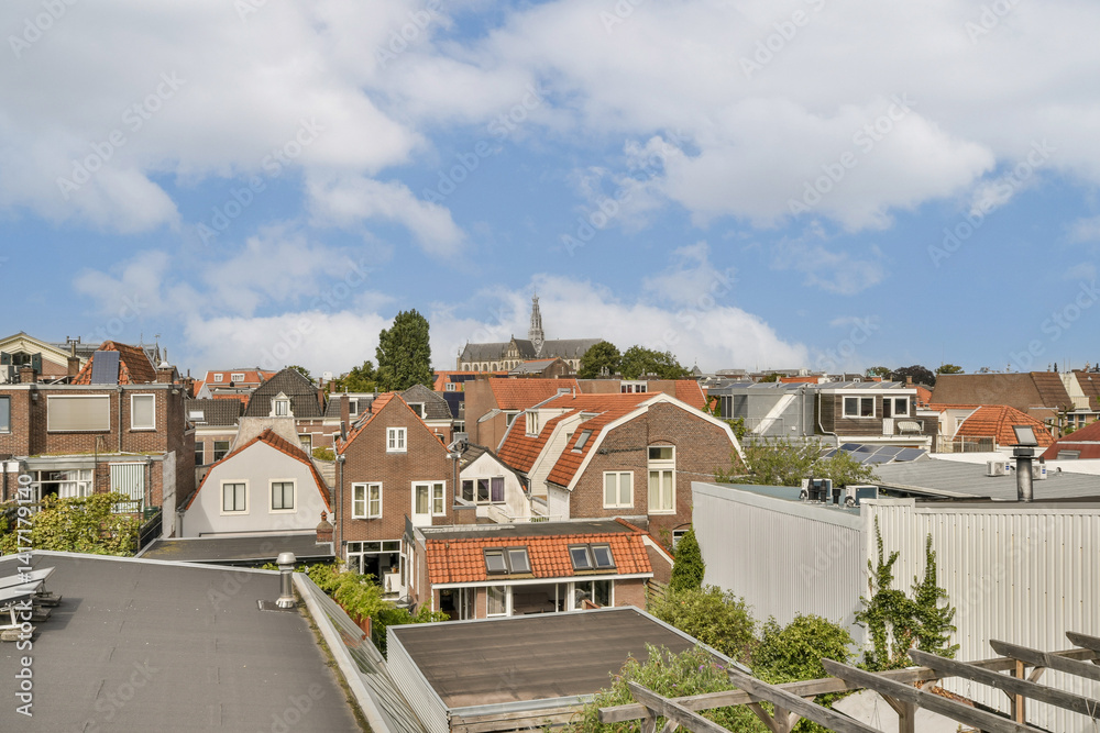 Obraz premium A scenic view of rooftops showcasing a blend of modern and historic buildings under a cloudy sky, illustrating urban beauty and architectural diversity.