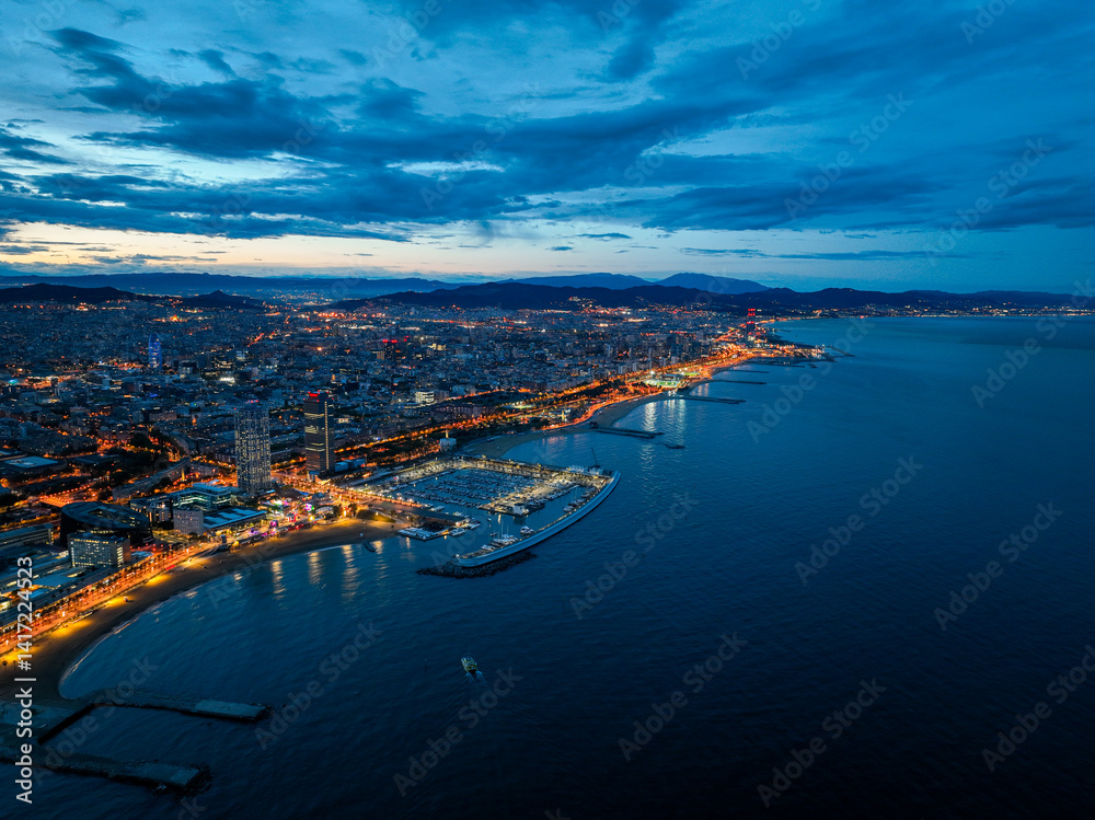 Fototapeta premium Coastal view of Barcelona marina and glowing skyline during twilight