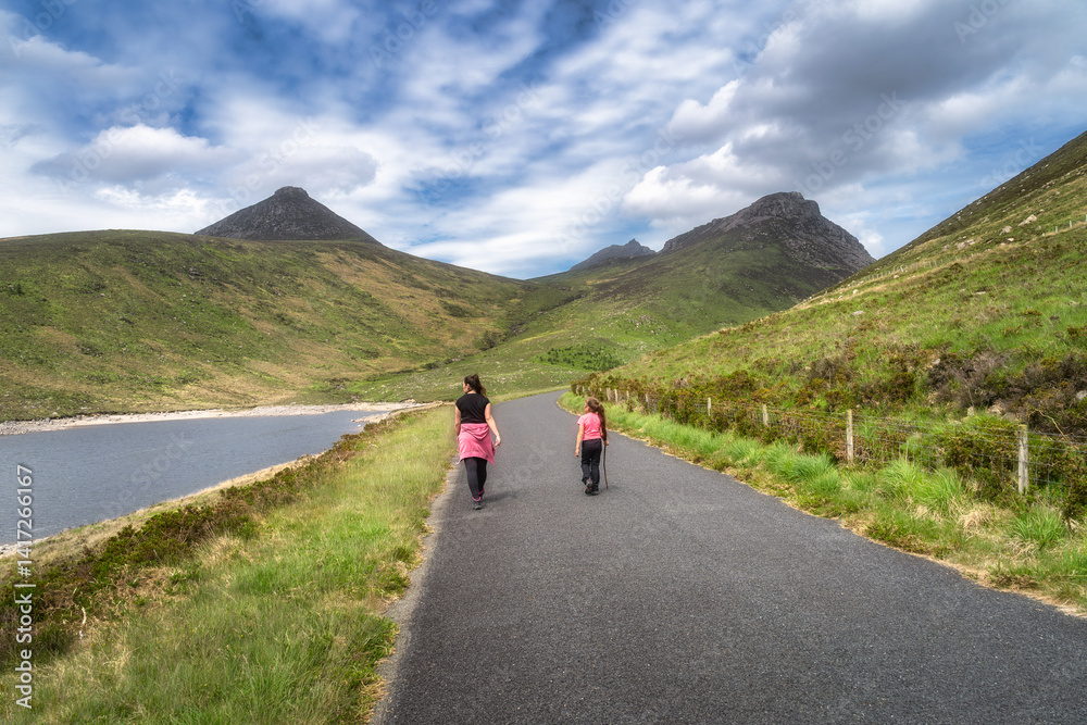 A family leisurely strolls through a stunningly picturesque landscape, surrounded by majestic mother and a serene, tranquil Silent Valley Reservoir that reflects the beauty of nature, Northern Ireland