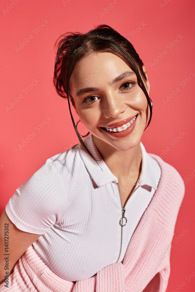 Joyful young woman smiling brightly in a vibrant studio setting with pink background