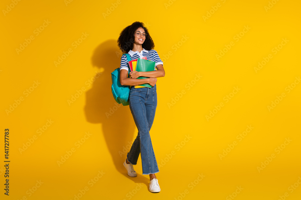 Young fashionable woman with books and backpack against a vibrant yellow background, embodying casual style, confidence, and joy. Young fashionable woman with books and backpack against a vibrant yellow background, embodying casual style, confidence, and joy.