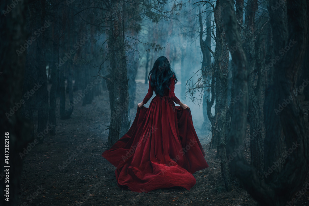 Fototapeta premium Art photo real person Gothic girl walking running in dark foggy forest trees, velvet red long medieval old style long dress train fly wind. Fantasy Woman Black hair back rear view fairy princess