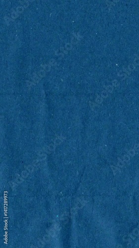Blue kraft paper noise texture vertical stop motion video. Old page overlay effect background loop animation. Vintage paper texture with crease, stain, grain, dust particles. Empty animated backdrop