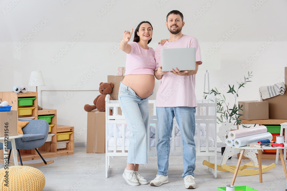 Young pregnant couple with laptop planning repair in children's room Young pregnant couple with laptop planning repair in children's room