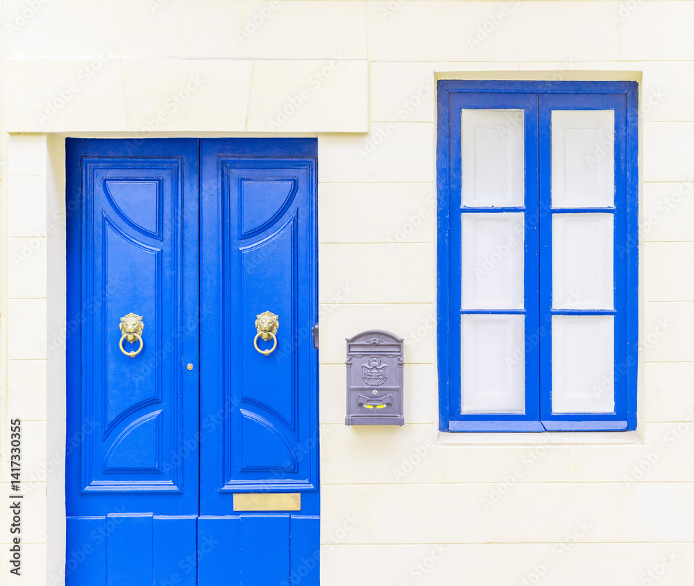 White brick wall with a blue window, door and a grey metal mail box