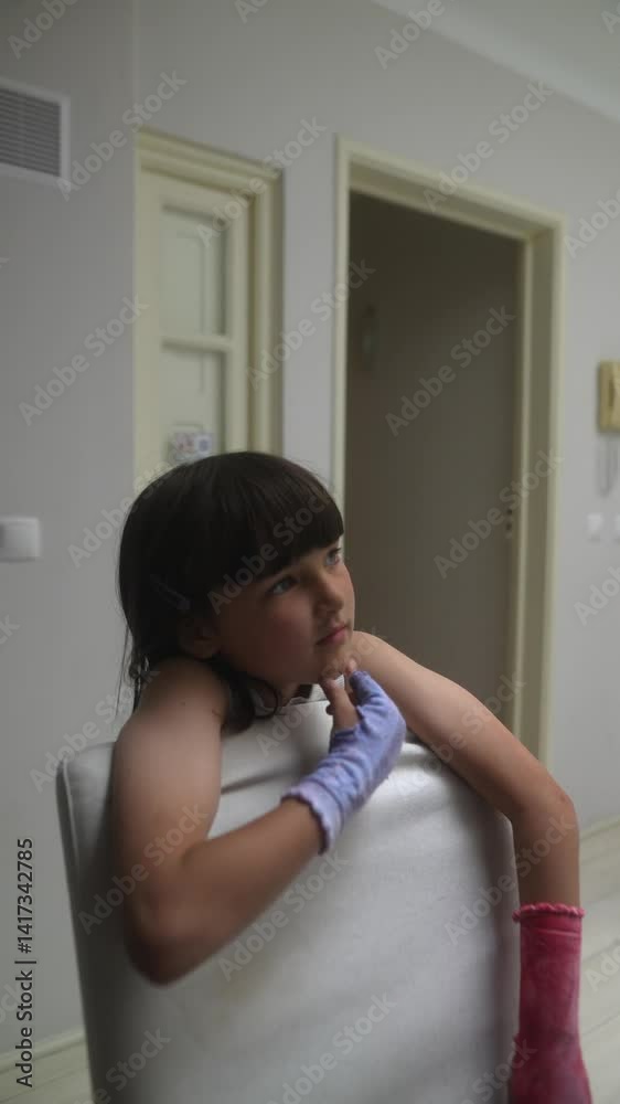 A Thoughtful Child is Relaxing Comfortably at Home while Wearing Colorful Gloves A Thoughtful Child is Relaxing Comfortably at Home while Wearing Colorful Gloves