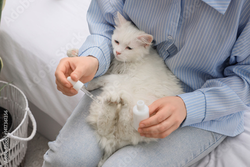 Woman applying oil onto cat...