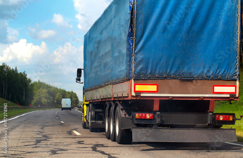 Transportation of consolidated cargo for online stores by trucks with semi-trailers along the highway in the summer. Insurance of cargo and vehicles of transport companies. Copy space for text