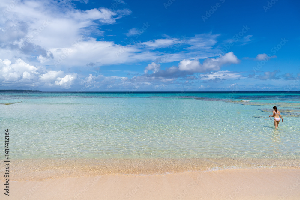 Woman with snorkel enters crystal-clear water for snorkeling in Okinawa, Japan