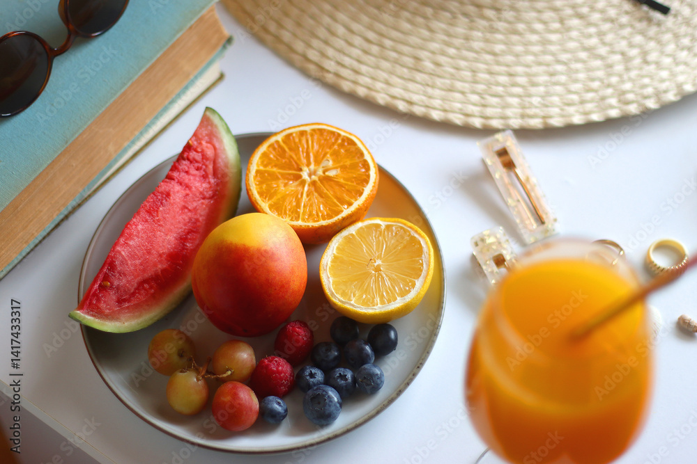 Glass of cocktail, straw hat, sunglasses, books, fresh fruit, chocolate and accessories. Summer essentials on the table. Selective focus.