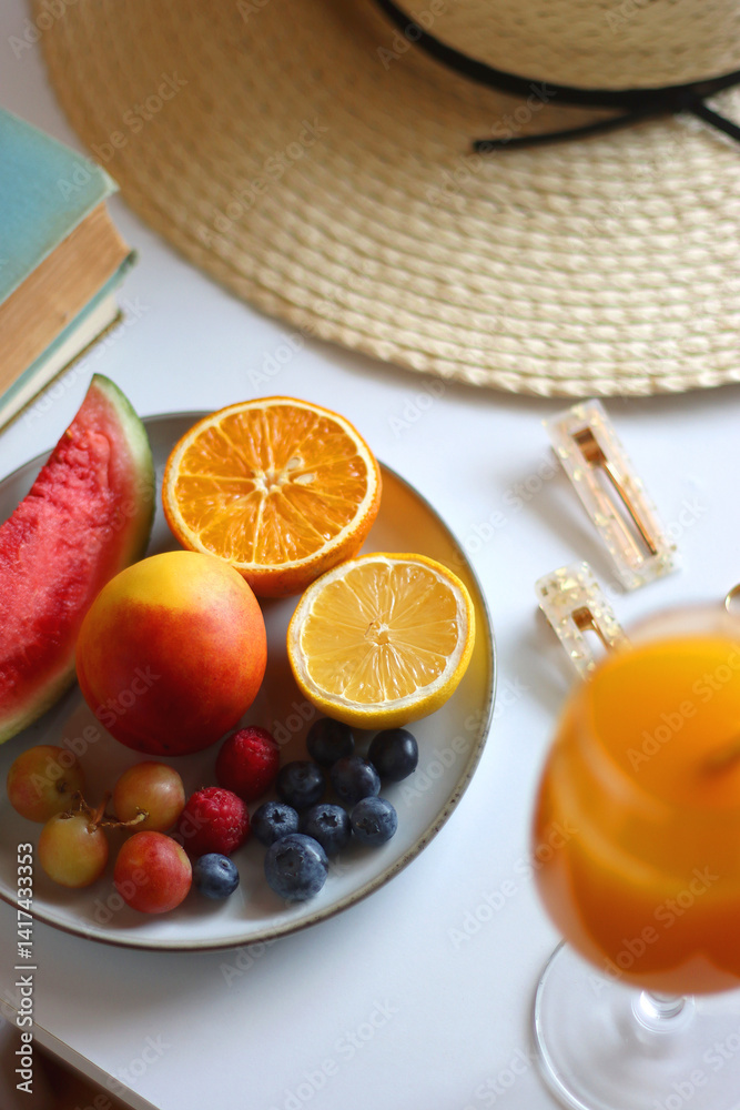 Glass of cocktail, straw hat, sunglasses, books, fresh fruit, chocolate and accessories. Summer essentials on the table. Selective focus.