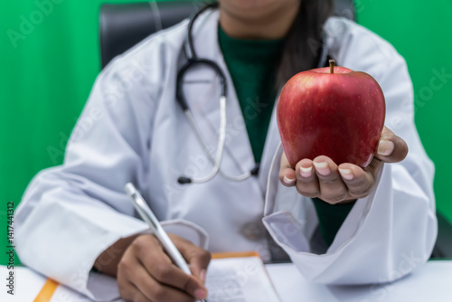 Female doctor offering red apple closeup - Concept of healthy food and nutrition.