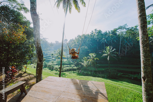 Beautiful girl visiting the Bali rice fields in tegalalang, ubud. Using a swing over the jungle. Concept about people, wanderlust traveling and tourism lifestyle