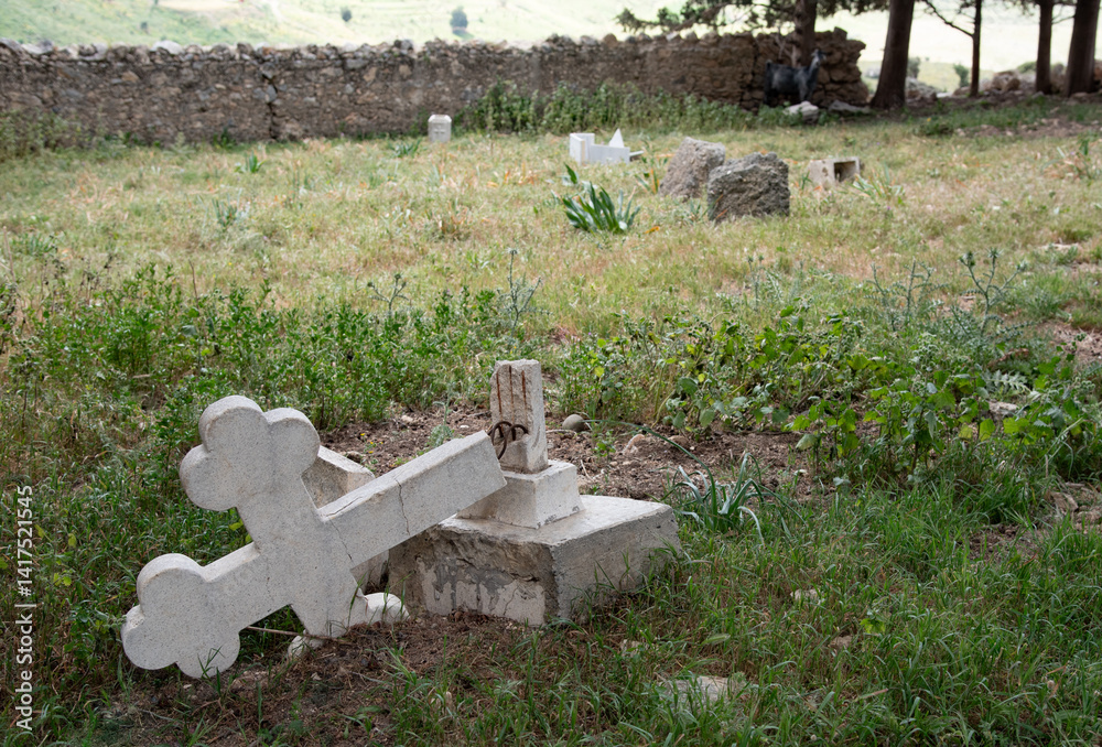 Broken white marble cross laying on the ground in cemetery