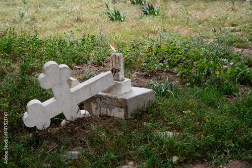 Obraz na płótnie Fallen cross lying on grass symbolizing loss and grief. Ruined orthodox cemetery w salonie