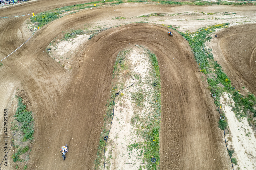 Motocross racers riding on dirt track. Drone aerial view of the motocross circuit
