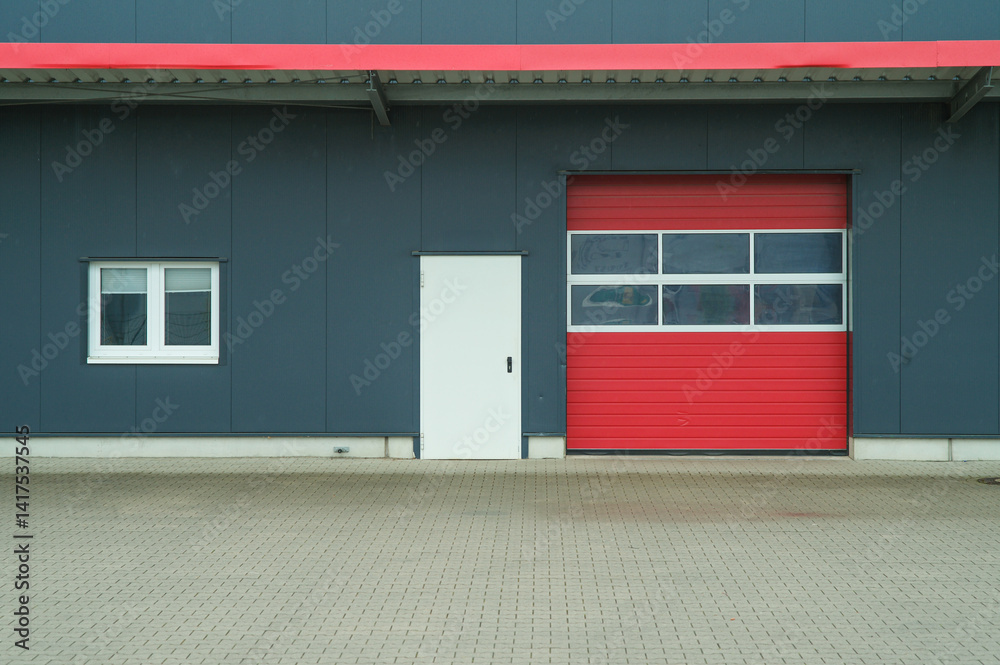 Fototapeta premium Red garage door and white side door of modern industrial building
