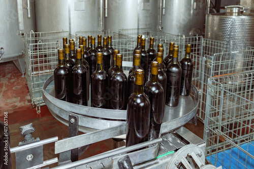 Wine bottles filled and sealed are moving along a conveyor belt, ready for labeling and packaging in a modern winery, showcasing the final stages of wine production