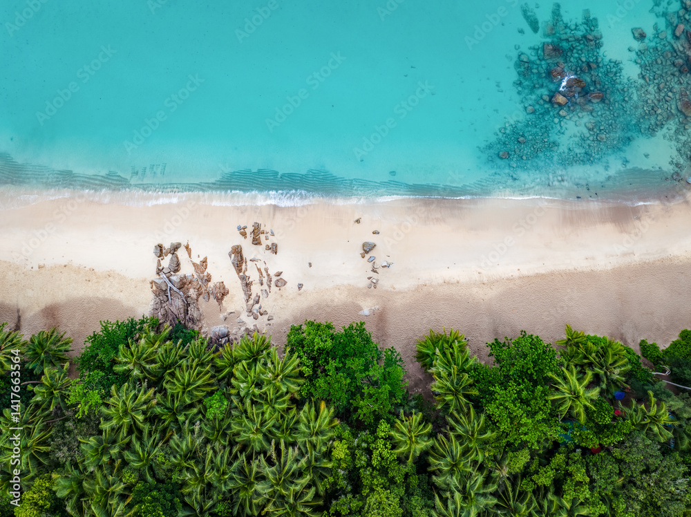 Aerial view of Freedom Beach in Phuket, Thailand, with turquoise waters, tropical forest, white sand, and rocks creating a pristine and exotic coastal landscape.