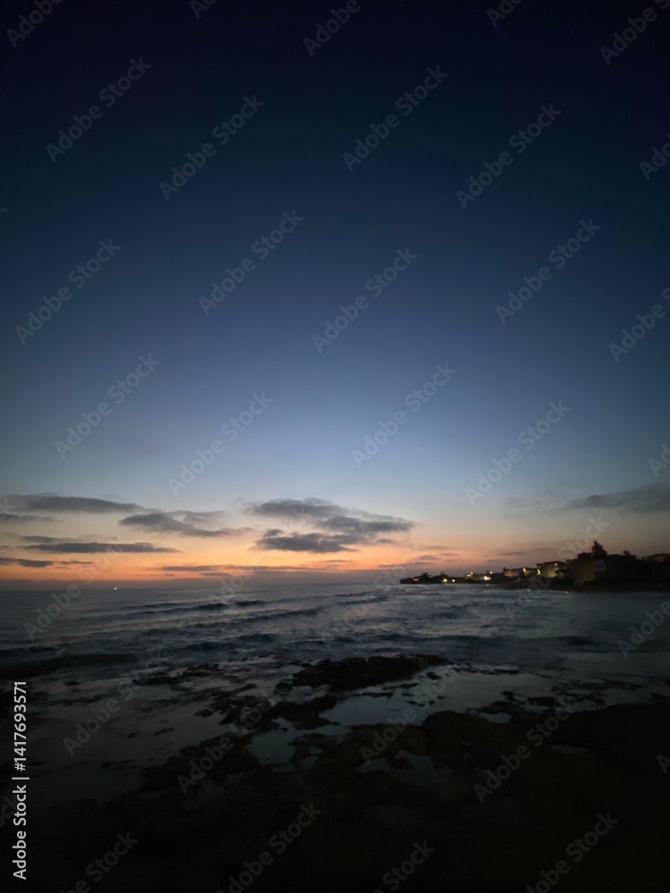 Fototapeta premium Vibrant sunset illuminating coastal landscape near Santa Croce Camerina, painting Sicilian sky with warm gradient hues