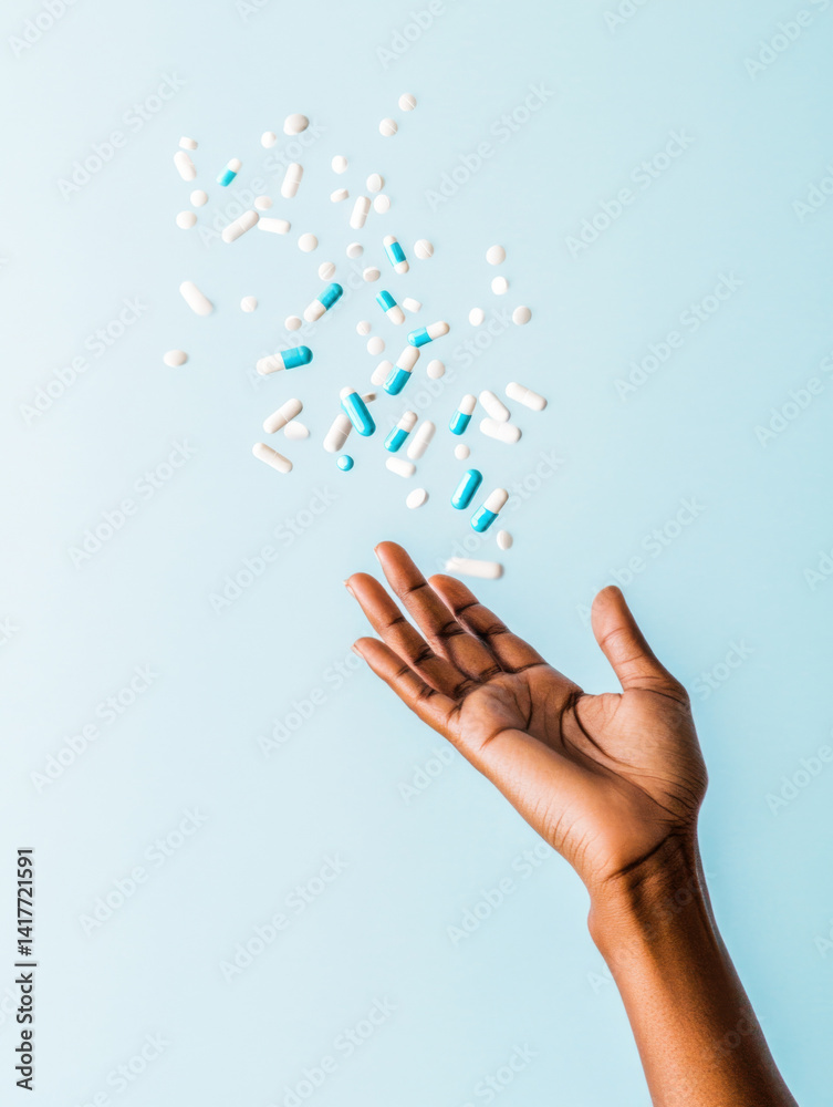Hand reaching out toward floating blue and white pills on a light blue background