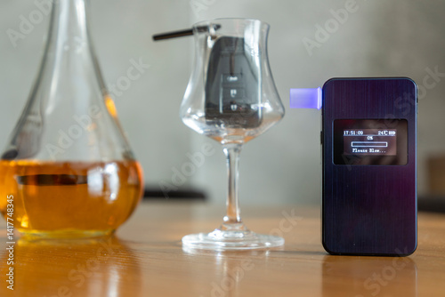 Obraz na plátně Alcohol breathalyzer next to a glass of whiskey,