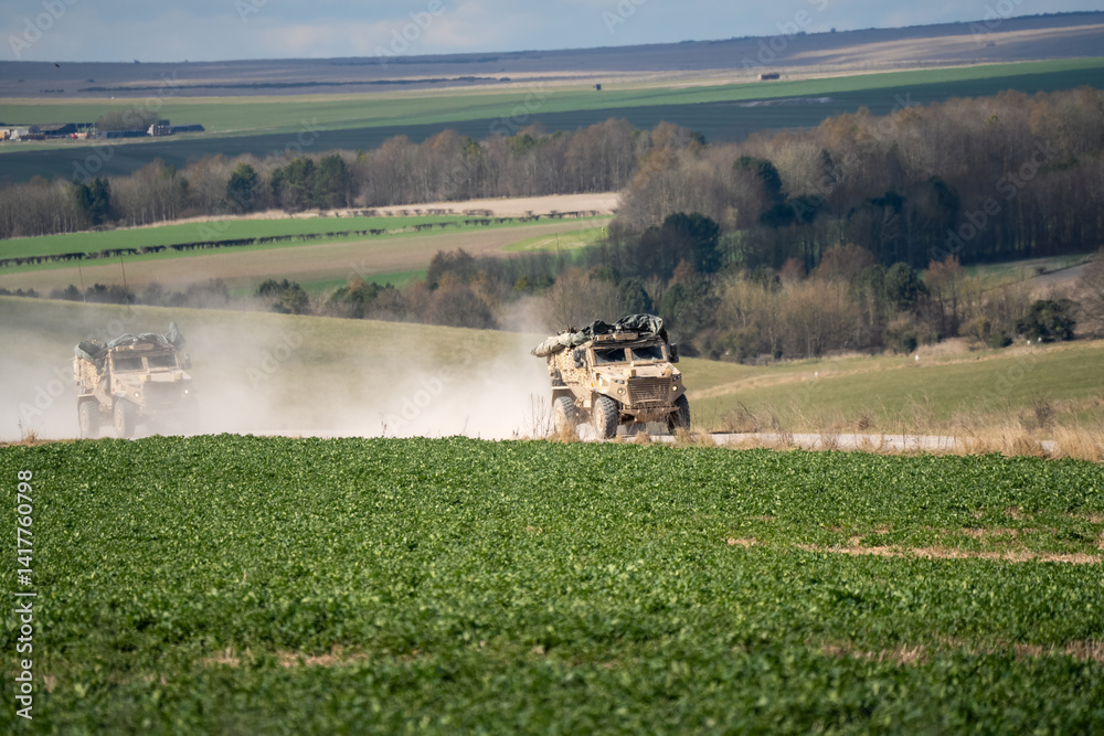 a British army Foxhound rapid support vehicle movong along a dirt track at speed
